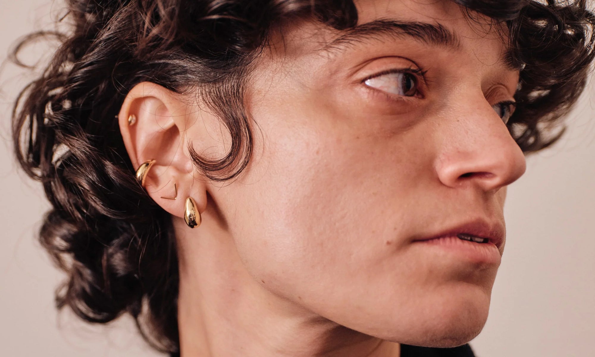 Model Erika Rodriguez wears the Diamond Mini Orb Stud, Delphi Ear Cuff, V Stud, and Sanguine Stud Earring. All handmade in recycled 14k gold.