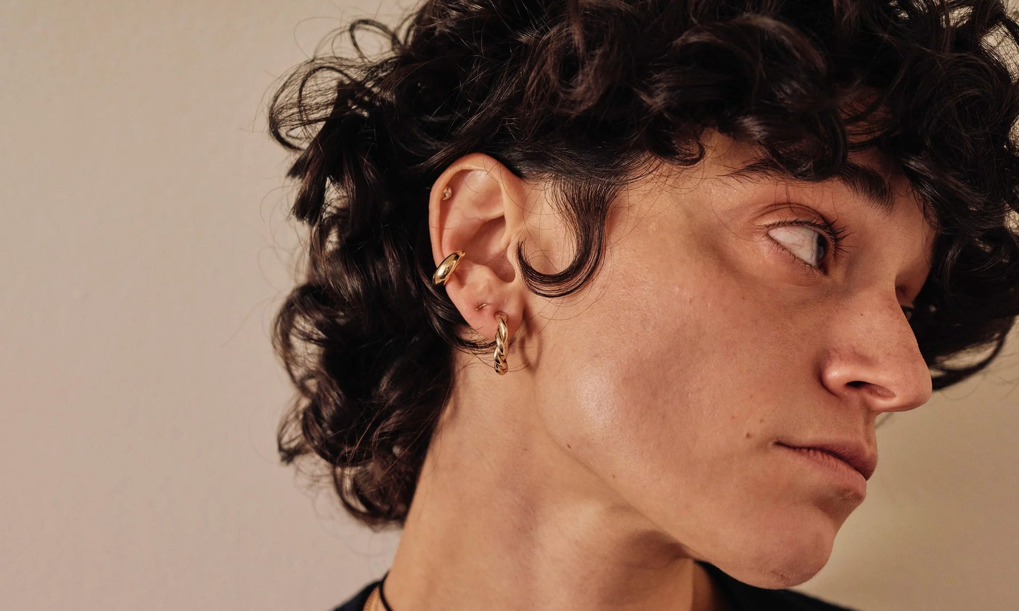 Model Erika Rodriguez wears the Diamond Mini Orb Stud, Delphi Ear Cuff, Outward Arc Stud and Helix Hoops. All sustainably handmade in recycled 14k gold.