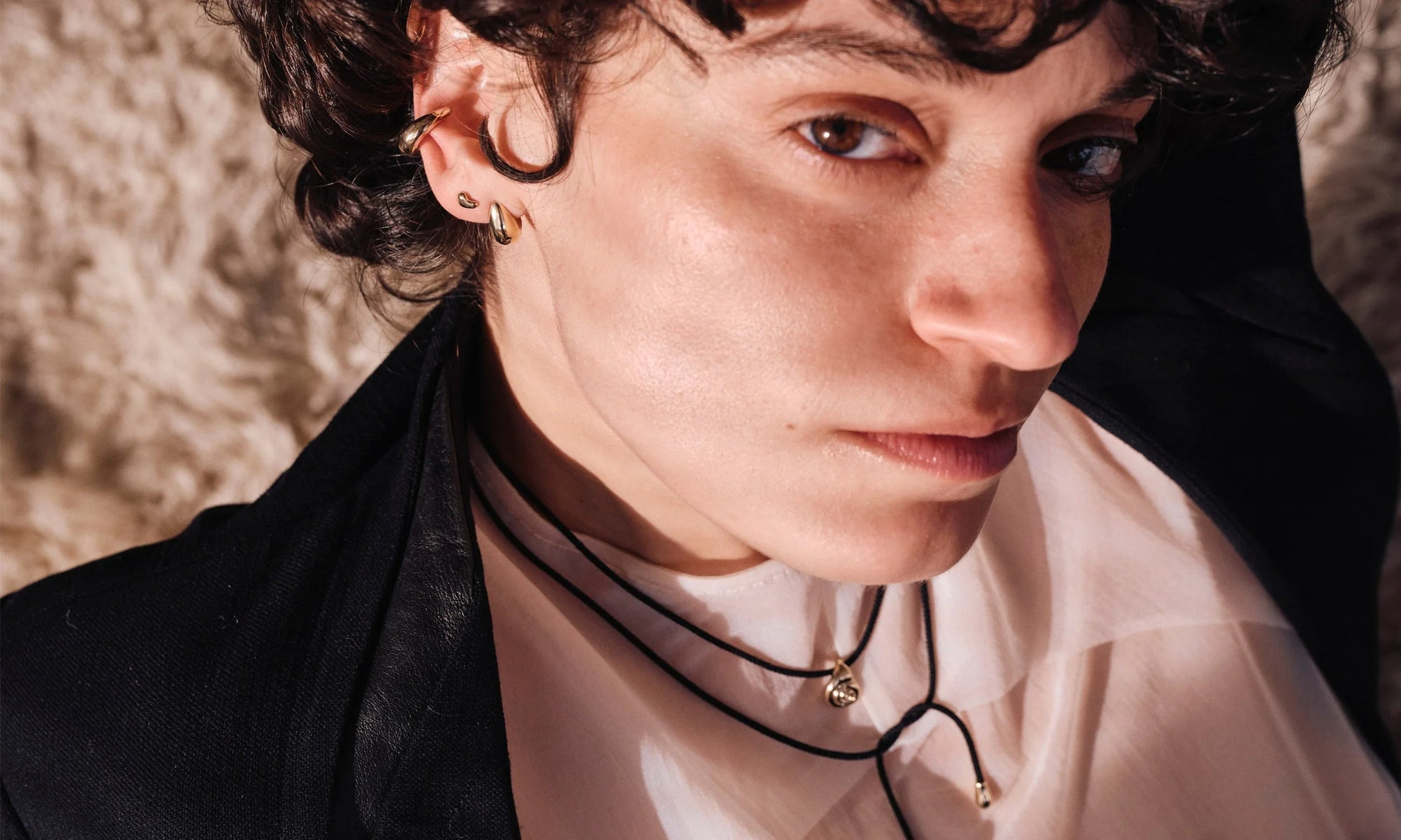 Erika lounges in the Growth Necklace on silk cord, along with the Delphi Ear Cuff, Diamond Mini Orb Stud, and Sanguine Stud Earrings. All handmade in recycled 14k gold.