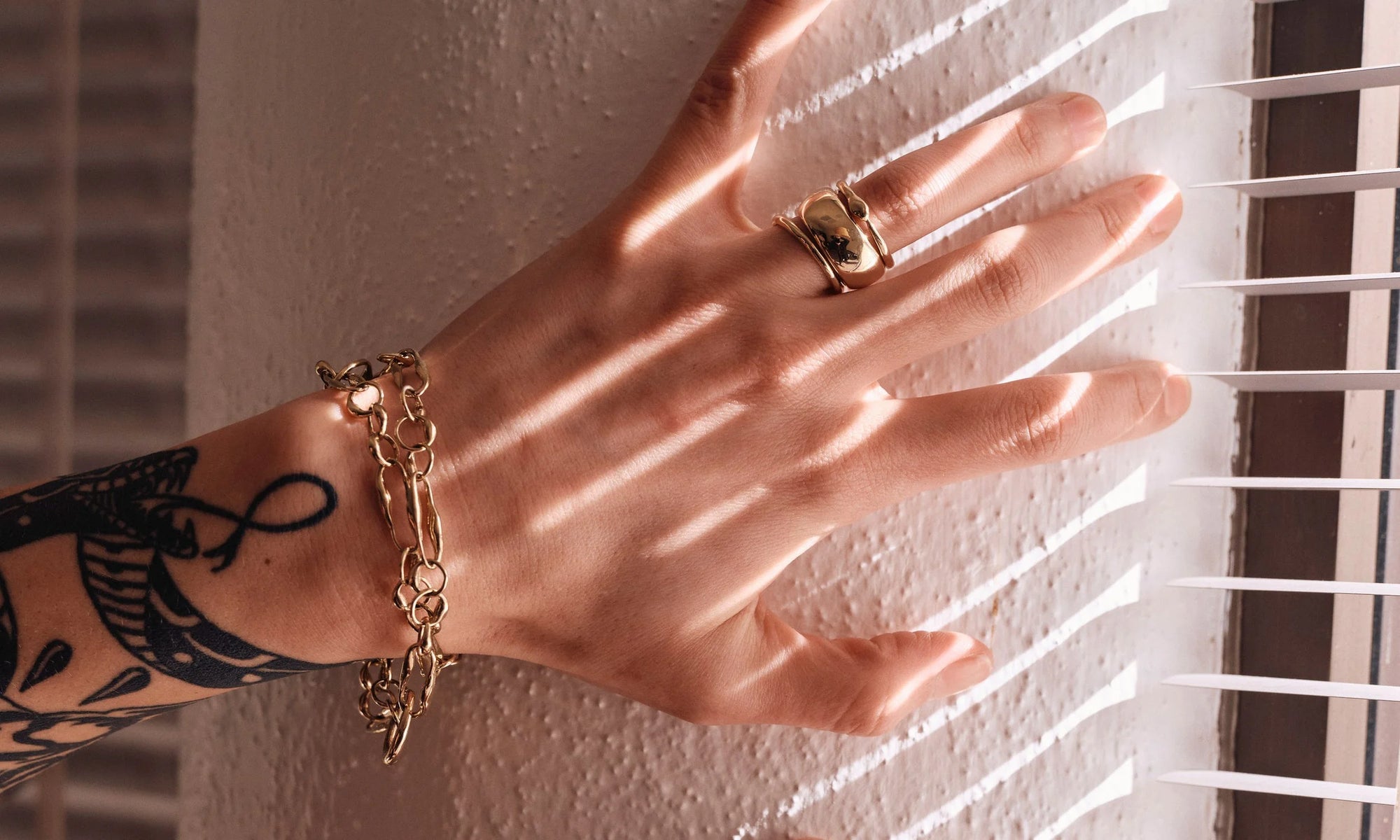 Erika wears the Metanoia Bracelet (doubled), the Portal Ring, Conjunct Cigar Band, and Ouroboros Ring. All handmade in recycled 14k gold.