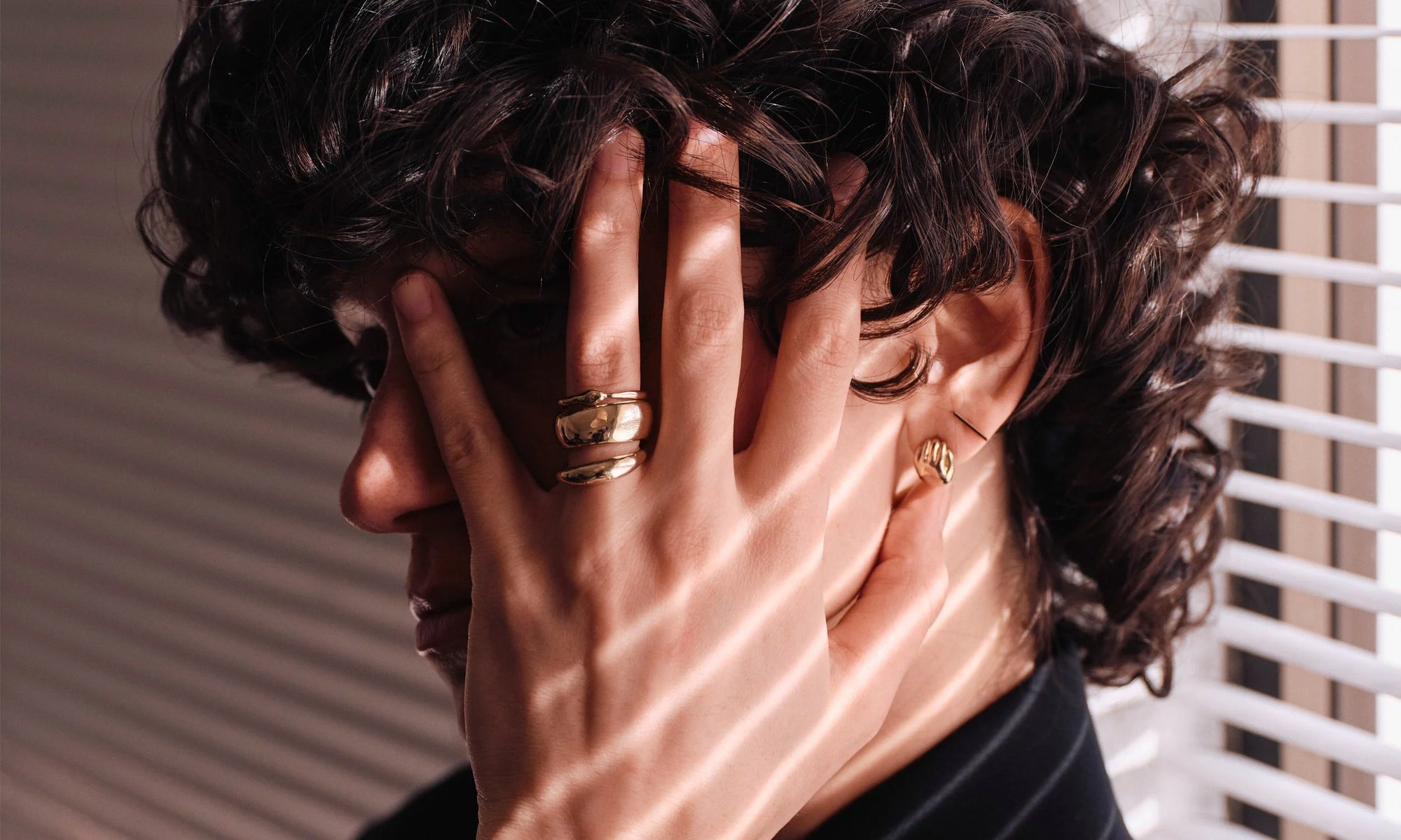Model Erika wears the Ouroboros Ring, Conjunct Cigar Band, and Portal Ring, along with the Held Earring and Linear Stud. All handmade in recycled 14k gold.