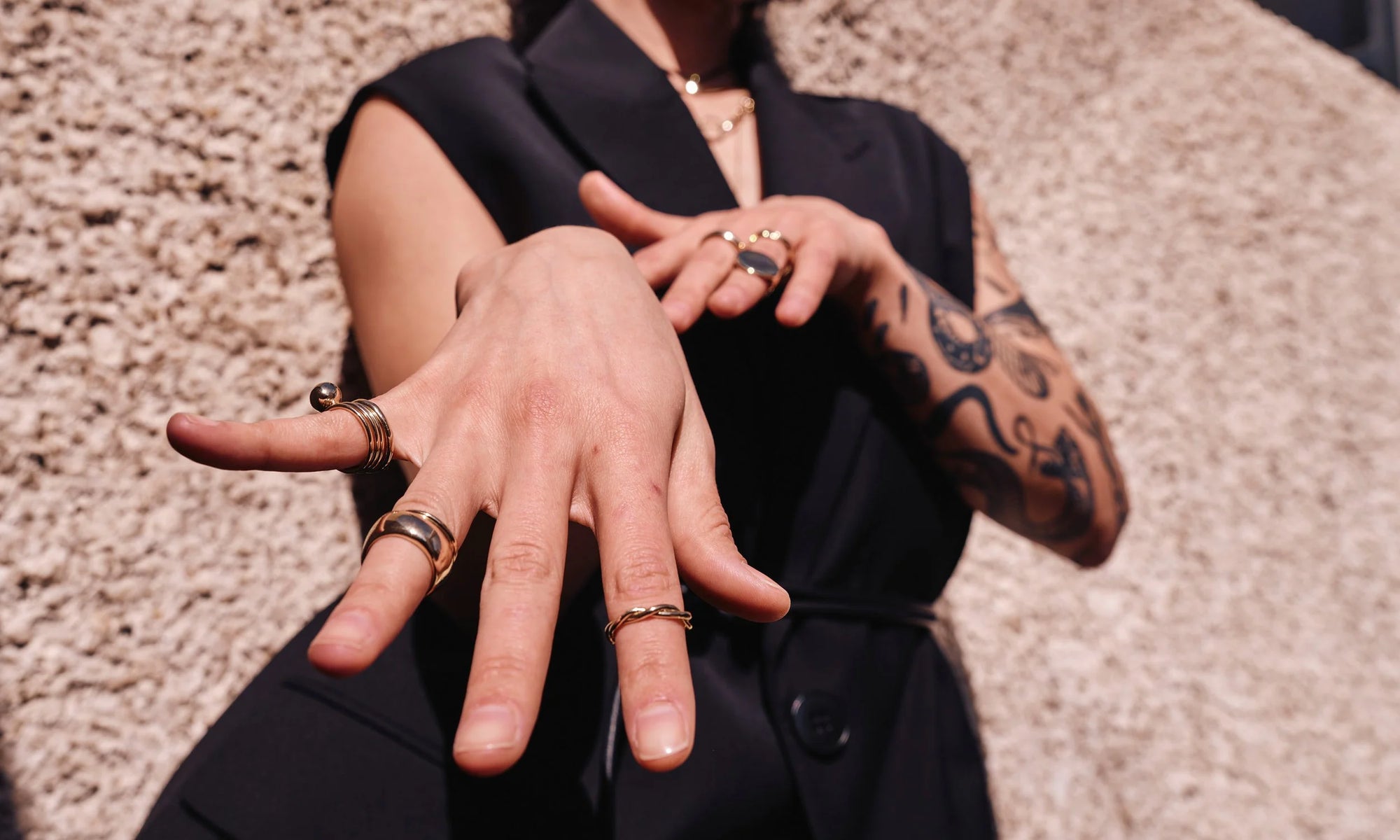 Erika wears, from left: the Infinite Ring Stack paired with the Central Sun Ring, Conjunct Cigar Band paired with Portal Ring, the Petite Twist Ring. All sustainably handmade in recycled 14k gold.