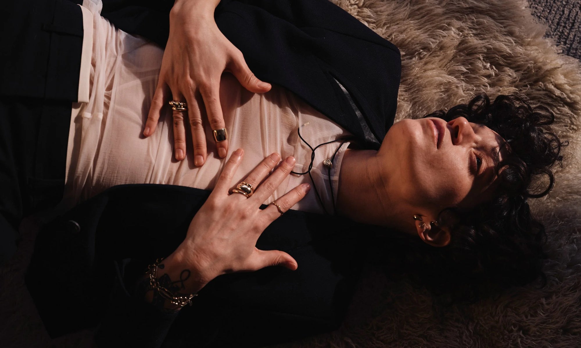 Erika wears, from top left: Helix Dome Band, Persephone Ring, Demeter Cigar Band, Metanoia Bracelet, Portal Ring, Conjunct Cigar Band, Ouroboros Ring, Wave Theory Ring, Growth Necklace on silk cord, Sanguine Drop Earrings, and Spiral Stud. All handmade in recycled 14k gold.