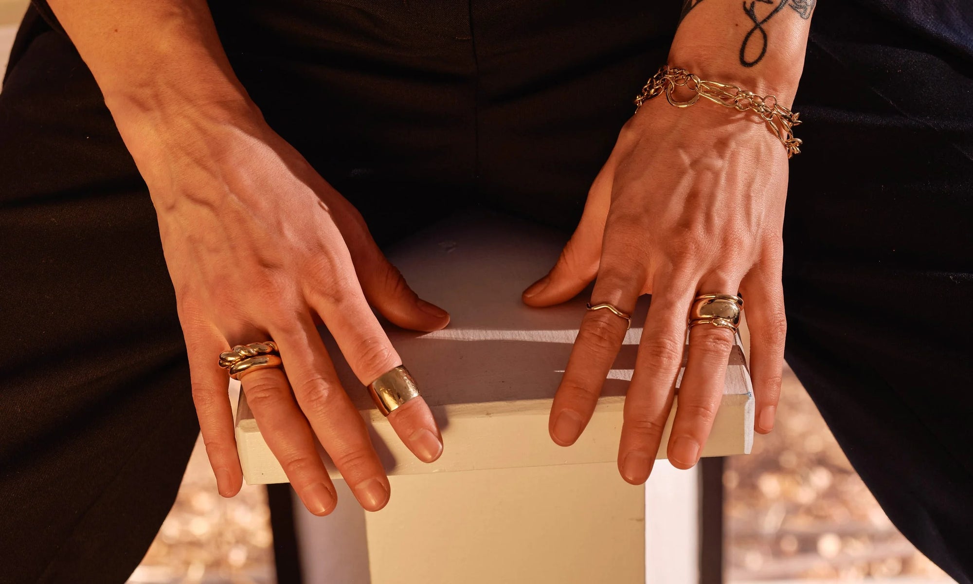 Erika wears, from left: the Helix Dome Ring, Persephone Ring, Demeter Cigar Band, Wave Theory Ring, Portal Ring, Conjunct Cigar Band, and Ouroboros Ring, along with the Metanoia Bracelet (worn doubled). All handmade in recycled 14k gold.