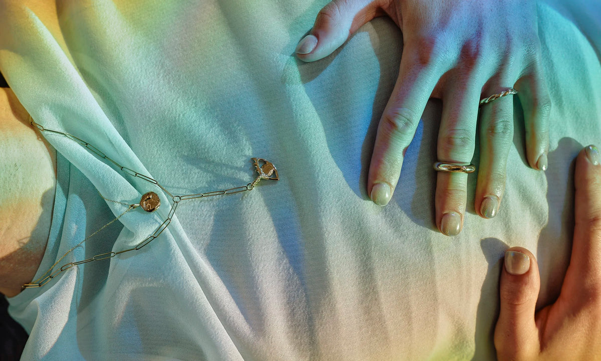 Handmade fine gold jewelry, hand-sculpted and ethically sourced by Talisman Fine Jewelry. Apple wears the Persephone Ring, Petite Helix Band, Protective Eye Y Necklace, and Alex Engraveable Amulet Necklace.