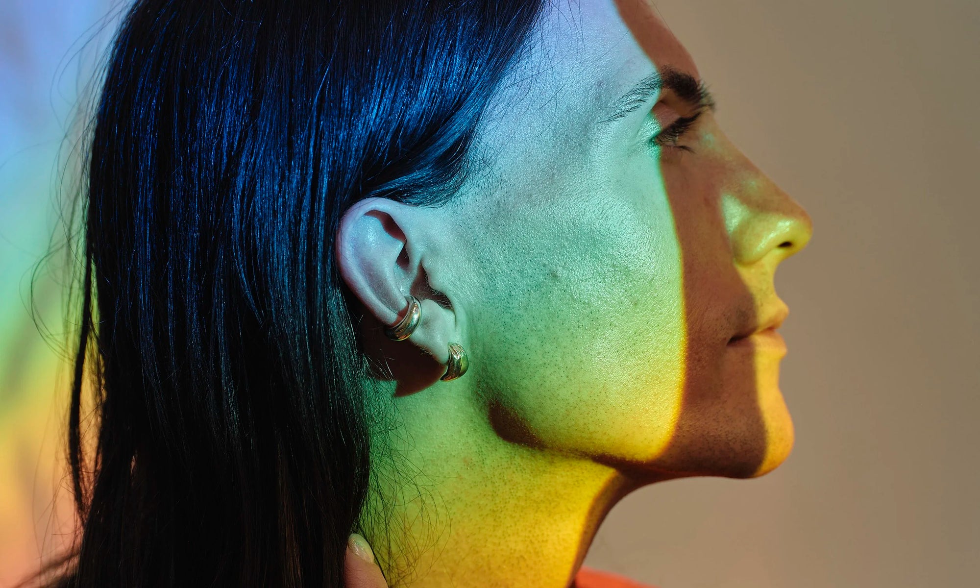 Handmade, minimal earrings cast in ethically-sourced recycled 14k gold, made by Talisman Fine Jewelry. Apple wears the Held Earring and Delphi Ear Cuff.