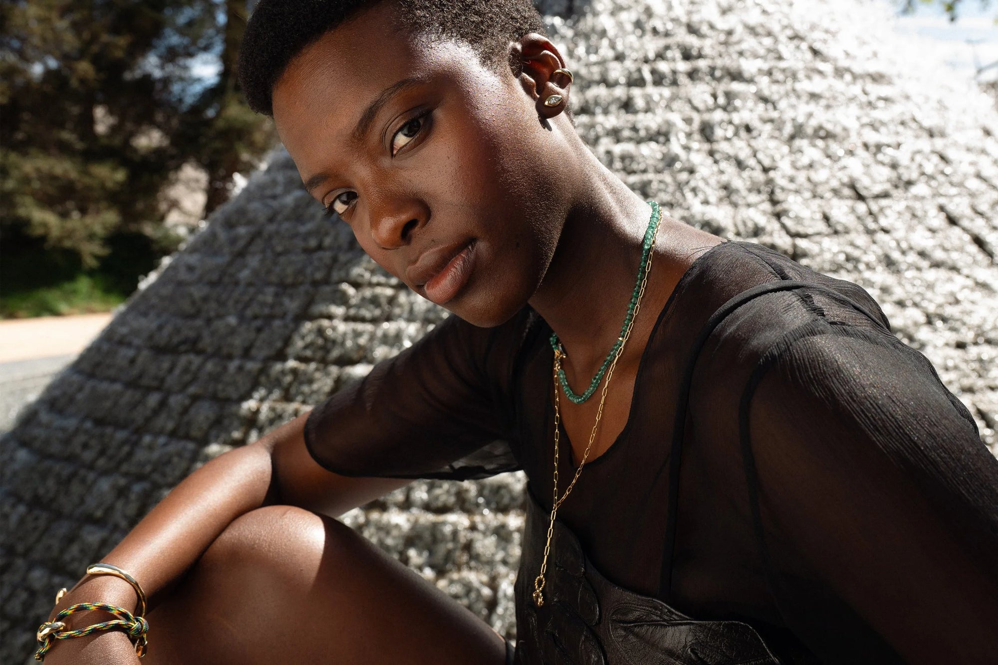 From top: Anna wears the Sibyl Ear Cuff and marquise diamond Horus Studs, the Prayer Necklace in Emerald, the updated Protective Eye Necklace, and the Inverse Cuff and Dance Bracelet. All handmade in recycled 14k gold.
