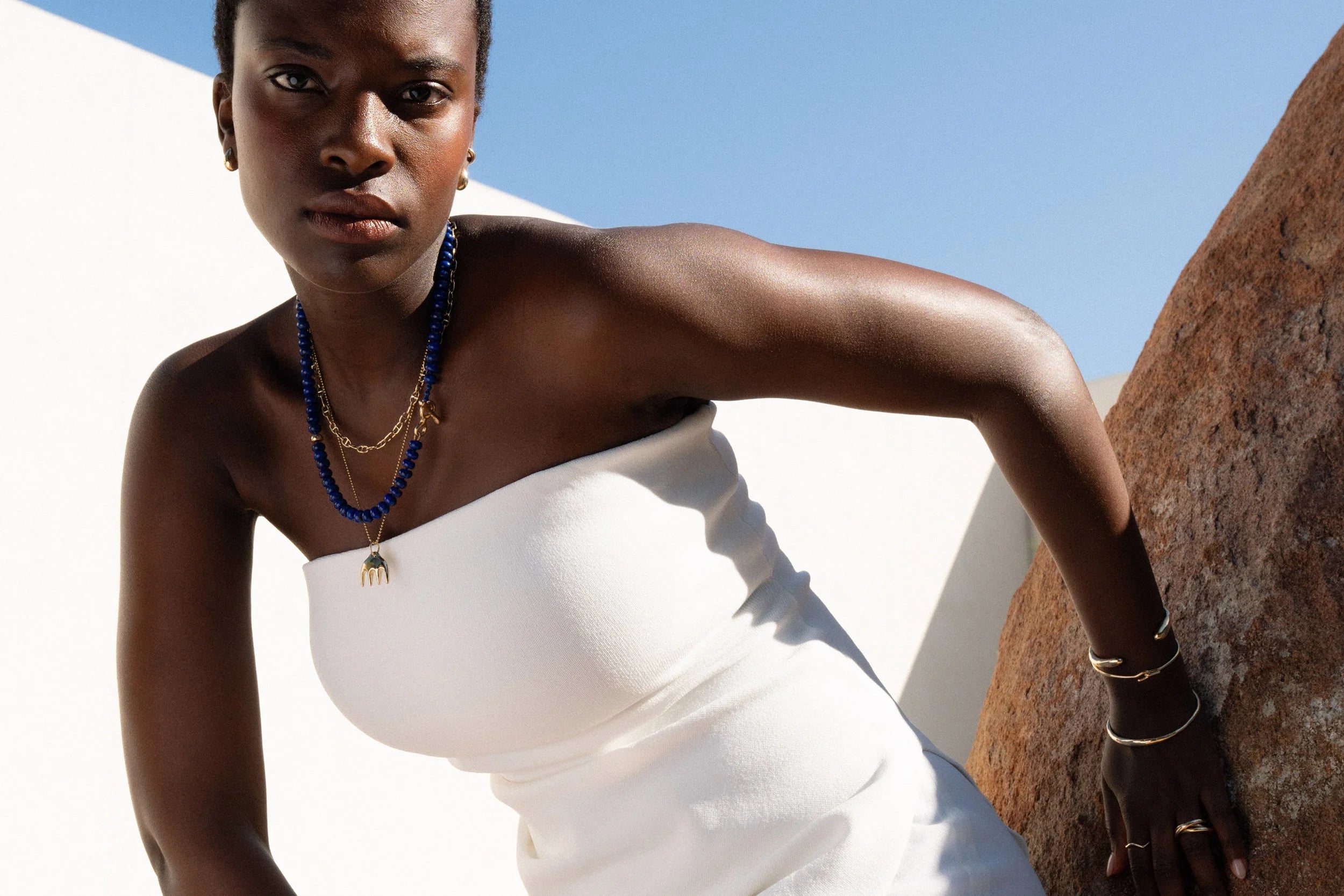 Anna layers the Metanoia Handmade Chain, the Prayer Necklace in Lapis, and Ariel's Comb Necklace. On the wrist: the Inverse Cuff, Orbit Bracelet, Portal Bracelet.